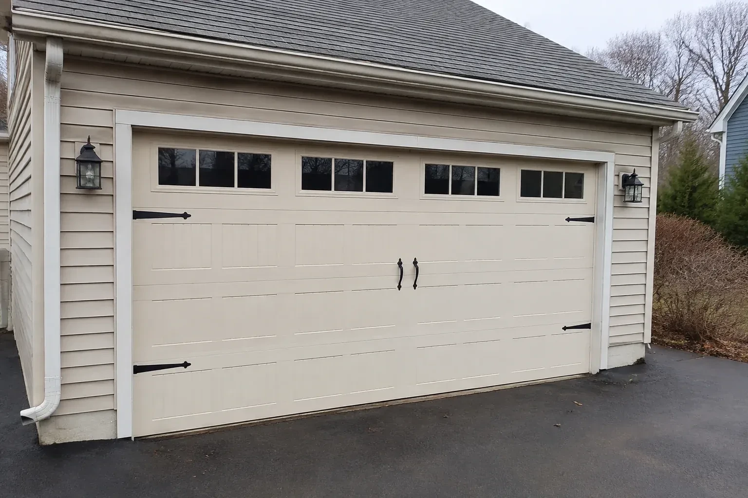 Cream carriage-house-style garage door with dark decorative hardware. — Carriage-House Garage Door Installation, Haldimand County