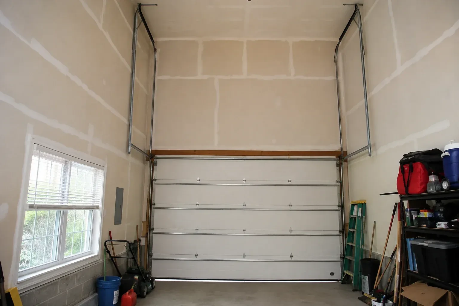 Tall garage interior with a sectional door and tracks extending into overhead space. — High-Lift Garage Door Conversion, Haldimand County